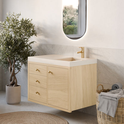 A modern bathroom featuring the Maine Made Single Door, Triple Drawer Vanity by Krovel Furniture Co., a gold faucet, oval mirror, potted plant, wicker basket with towels, and a round woven rug on a light marble floor.
