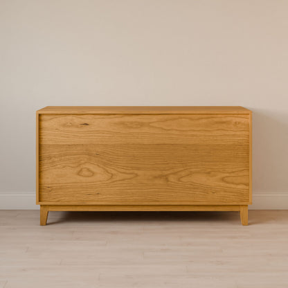 The Six Drawer Dresser in Cherry by Krovel Furniture Co. features a light, natural finish against a cream wall. With clean lines and simple design, it embodies sustainable construction and rests elegantly on a light wood floor.
