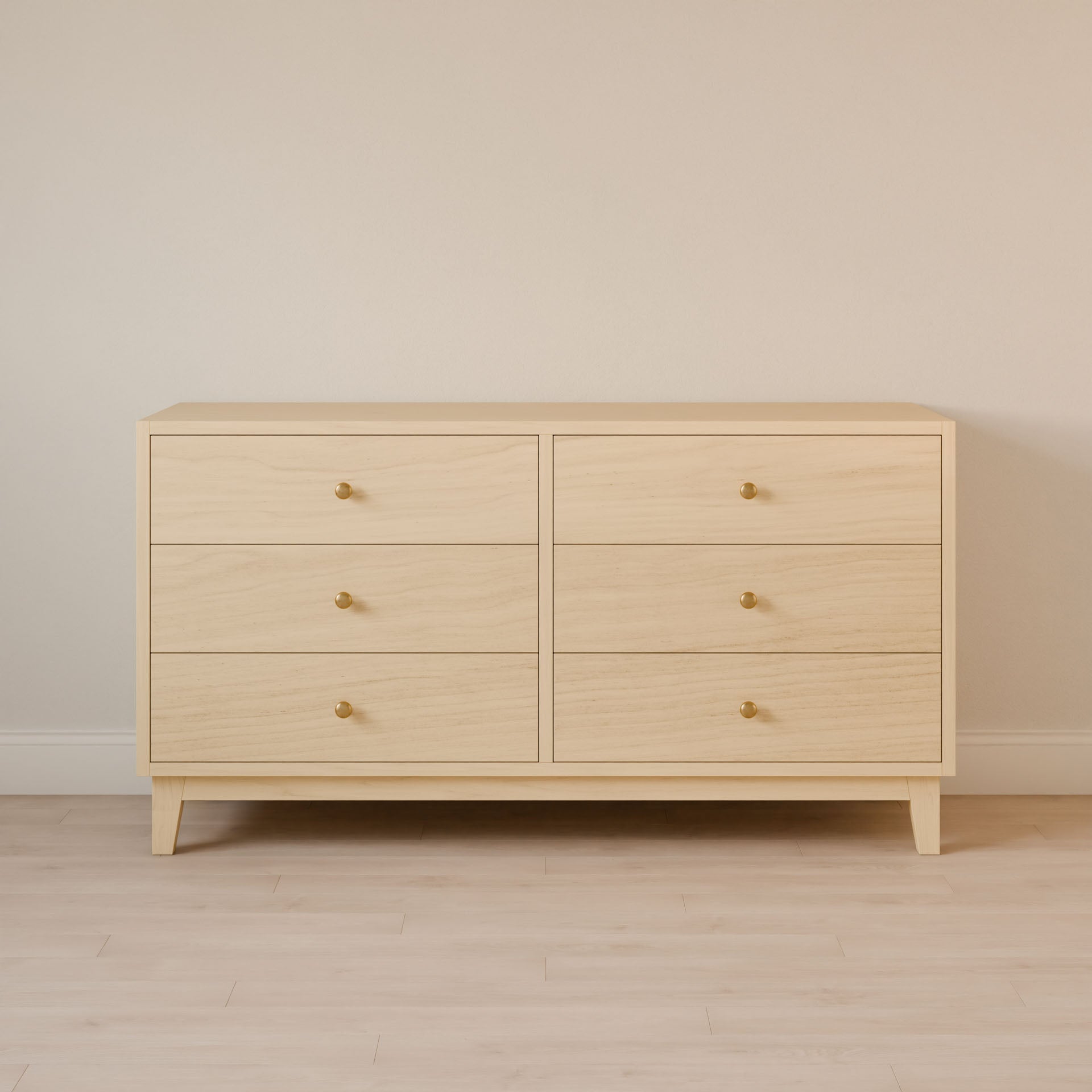 The Six Drawer Dresser in Maple by Krovel Furniture Co. is a minimalist piece made with premium plywood, featuring round brass knobs. It offers custom size options and sits elegantly on a light wood floor against a beige wall, embodying contemporary style with sustainable construction.