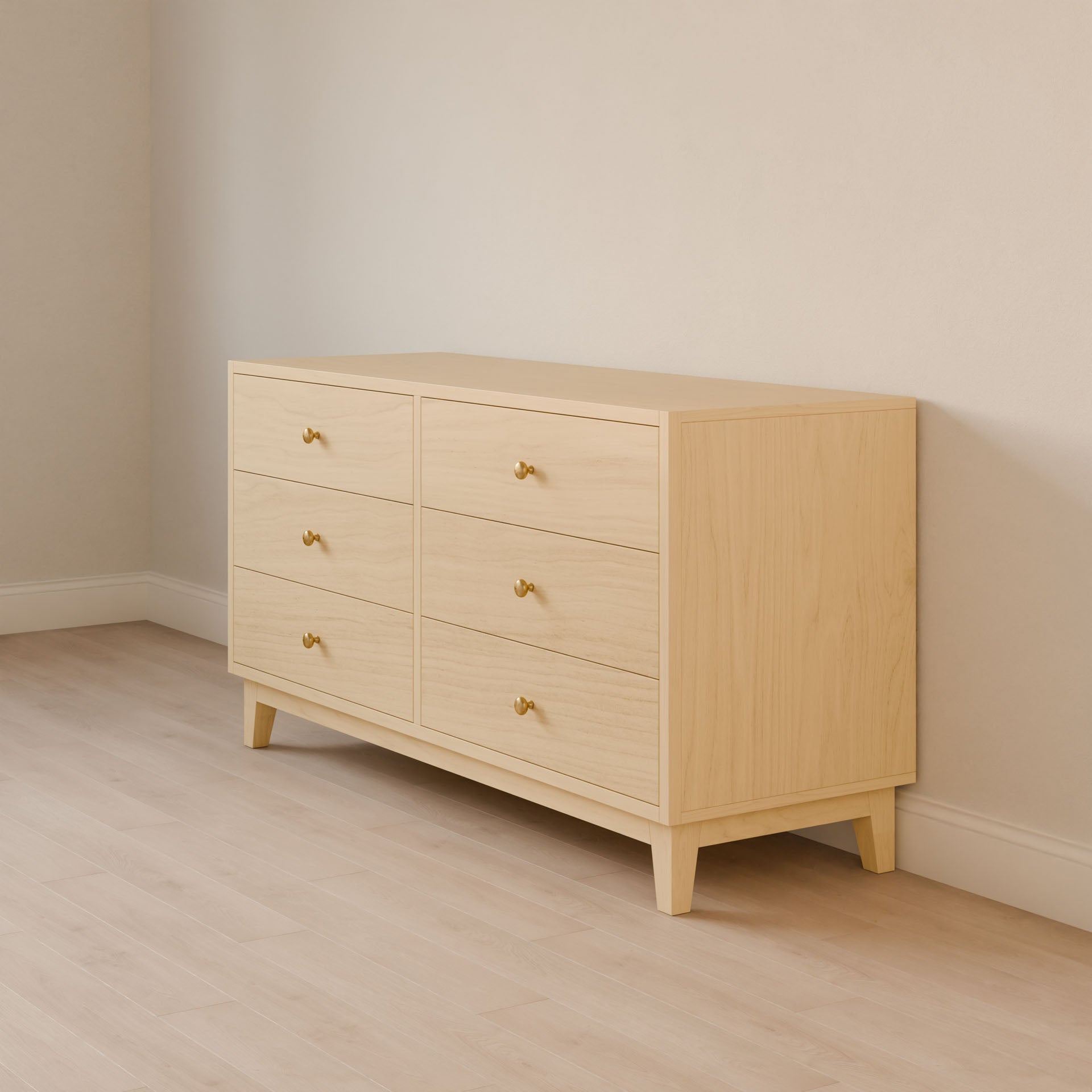 The Six Drawer Dresser in Maple by Krovel Furniture Co. stands against a beige wall on a light wood floor, showcasing sustainable construction and golden knobs, combining simple design with the elegance of premium plywood furniture.