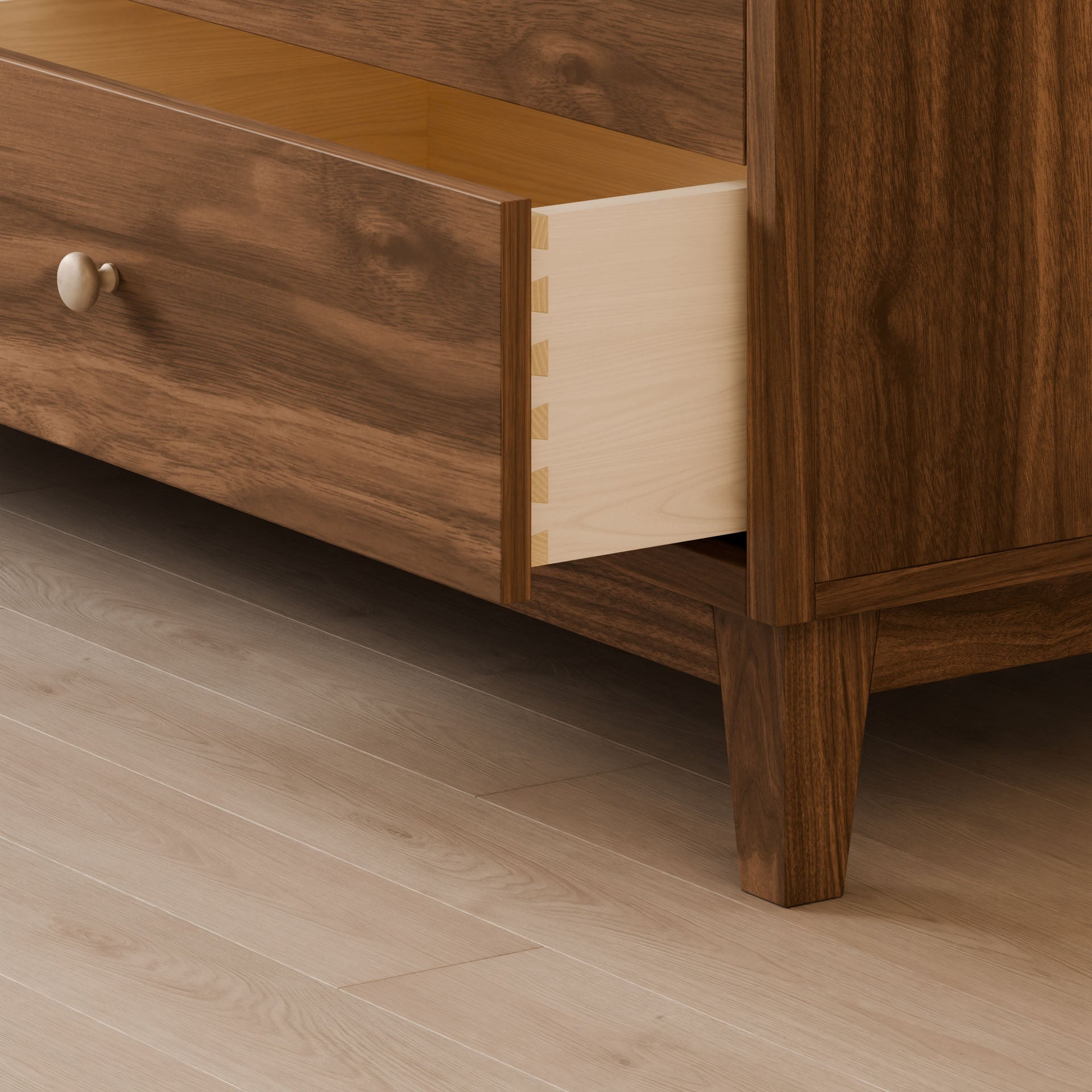 The Six Drawer Dresser in Walnut by Krovel Furniture Co. features a partially open drawer with dovetail joints, a solid hardwood face frame, and a smooth, rich brown finish displaying visible wood grain patterns. It stands on a light wood floor with a round, beige knob, showcasing sustainable craftsmanship.