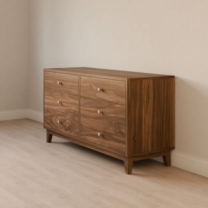 The Six Drawer Dresser in Walnut by Krovel Furniture Co. is elegantly crafted from premium cabinet grade plywood with a solid hardwood face frame. It features six drawers with small round knobs and stands against a light-colored wall on wooden flooring, showcasing its simple, modern design.