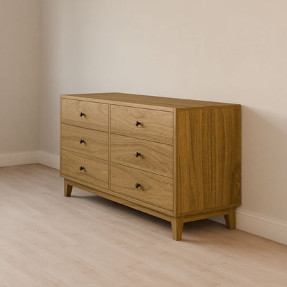 The Krovel Furniture Co. Six Drawer Dresser in White Oak, crafted from solid hardwood, features six drawers with small black knobs. Its smooth surface and natural grain offer a minimalist, clean look on a light wood floor against a light-colored wall, embracing sustainable construction.