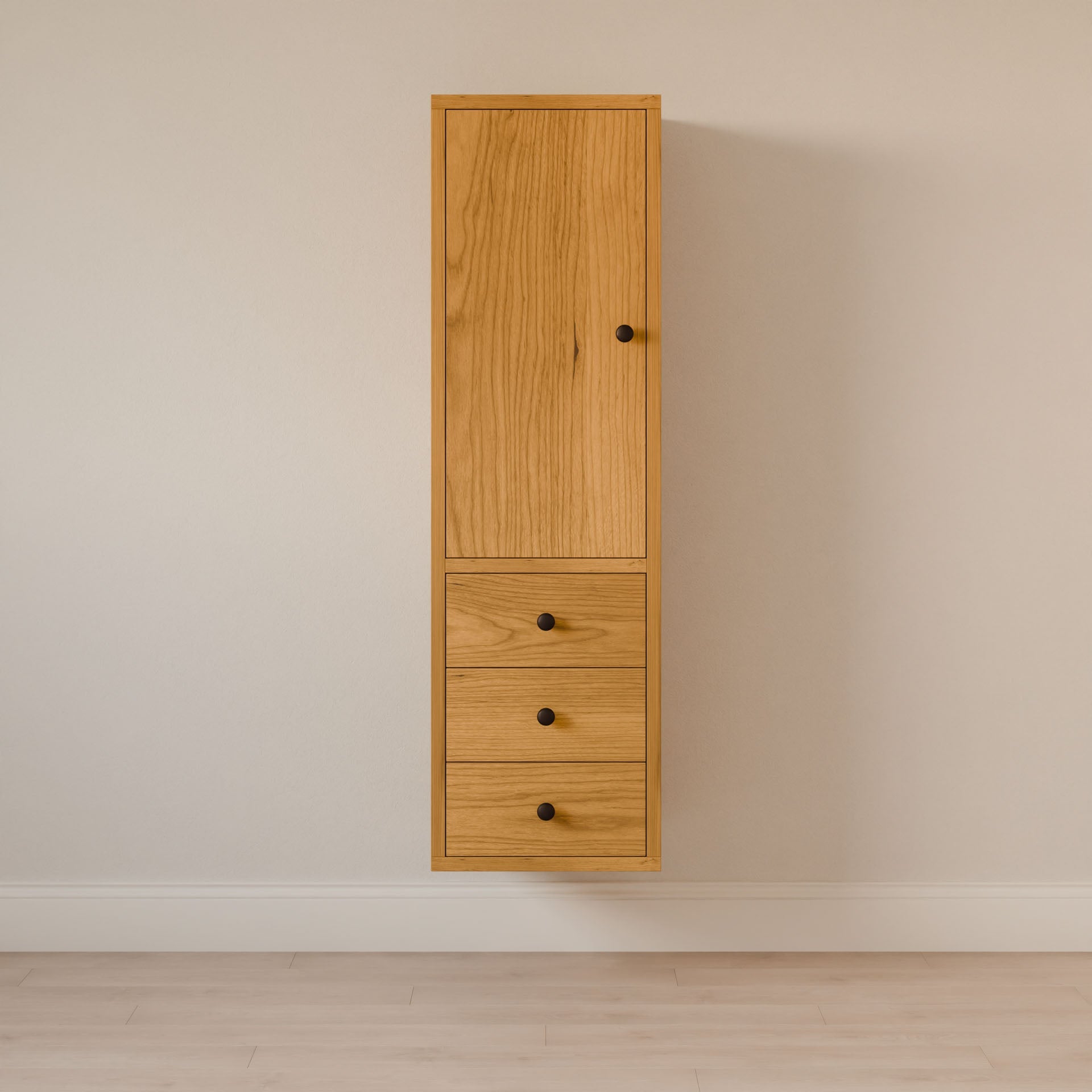 The Triple Drawer Linen Cabinet in Cherry by Krovel Furniture Co. is a wooden, wall-mounted piece with sustainable construction. It has a vertical door, three drawers with black knobs, and offers the style of an elegant bathroom vanity against a beige wall above a light wood floor.