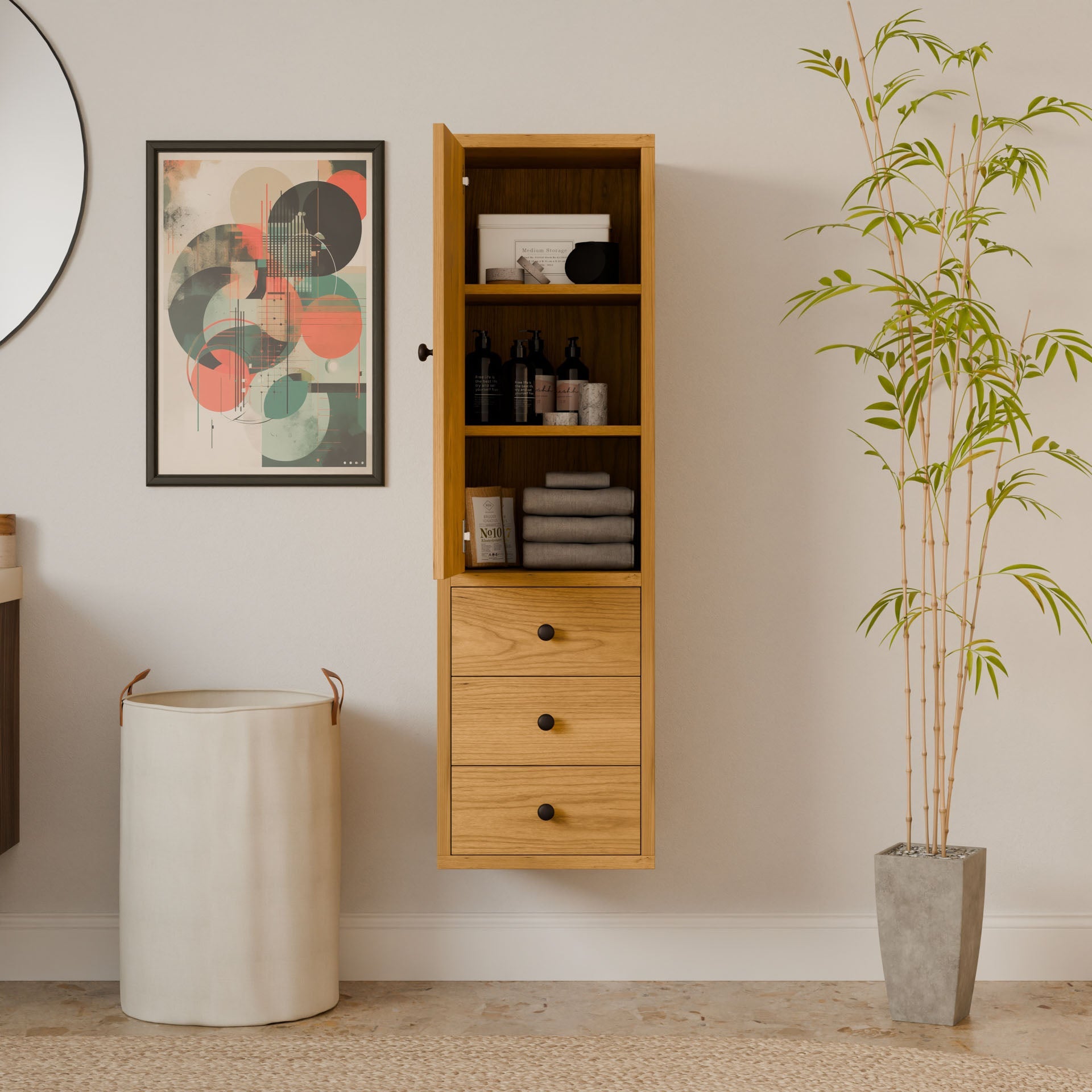 A modern interior showcases the Krovel Furniture Co.s Triple Drawer Linen Cabinet in Cherry wall-mounted with open shelves and drawers. Nearby, a tall plant in a stone pot, sustainable in design, a white cylindrical laundry basket, and an abstract art piece adorn the space.