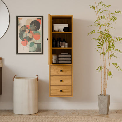 A modern interior showcases the Krovel Furniture Co.s Triple Drawer Linen Cabinet in Cherry wall-mounted with open shelves and drawers. Nearby, a tall plant in a stone pot, sustainable in design, a white cylindrical laundry basket, and an abstract art piece adorn the space.