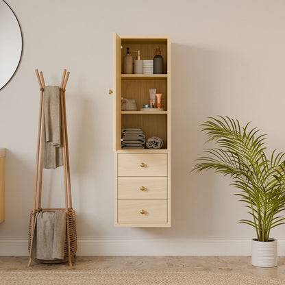 A modern bathroom includes a Krovel Furniture Co. Triple Drawer Linen Cabinet in maple, showcasing toiletries and folded towels on open shelves. A circular mirror adorns the wall, while soft-close drawers and a hardwood face frame add elegance. A wooden stand for towels and a potted plant complete the space.