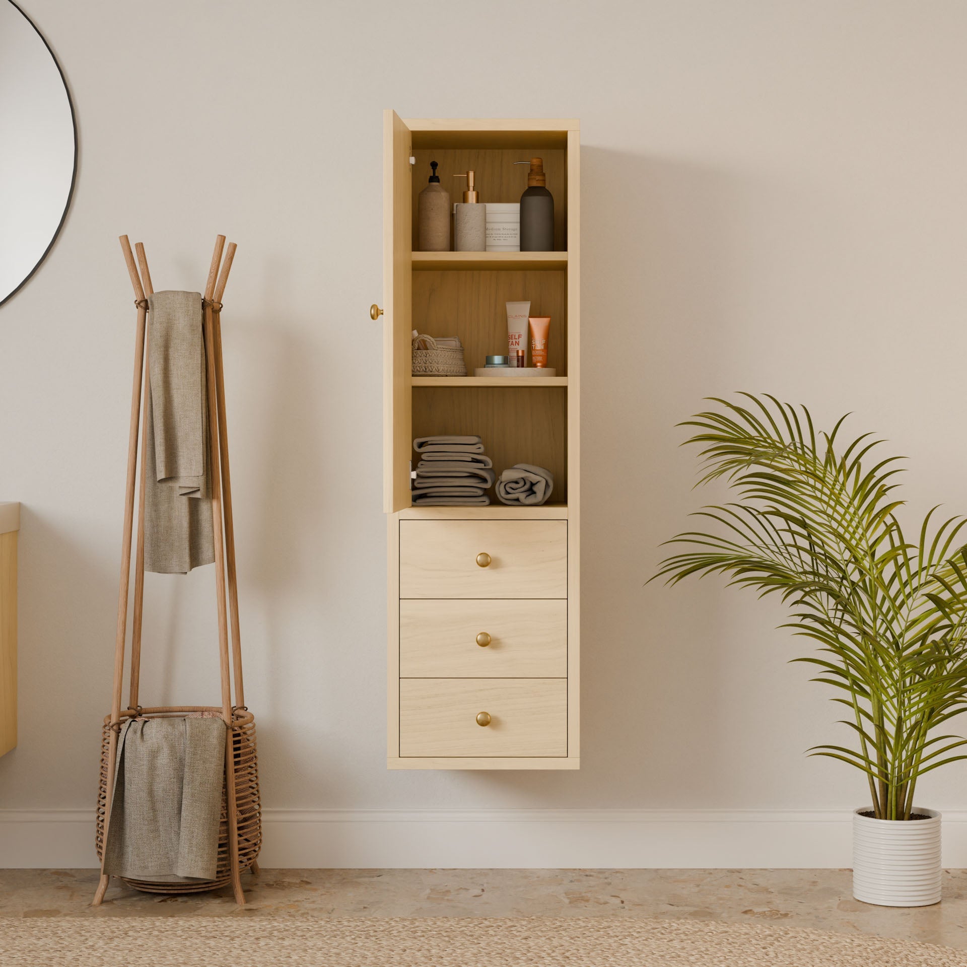 A modern bathroom features the Maine Made Triple Drawer Linen Cabinet by Krovel Furniture Co. for toiletries and towels, plus a towel rack with basket, round mirror, potted palm plant, and a light rug on the floor.