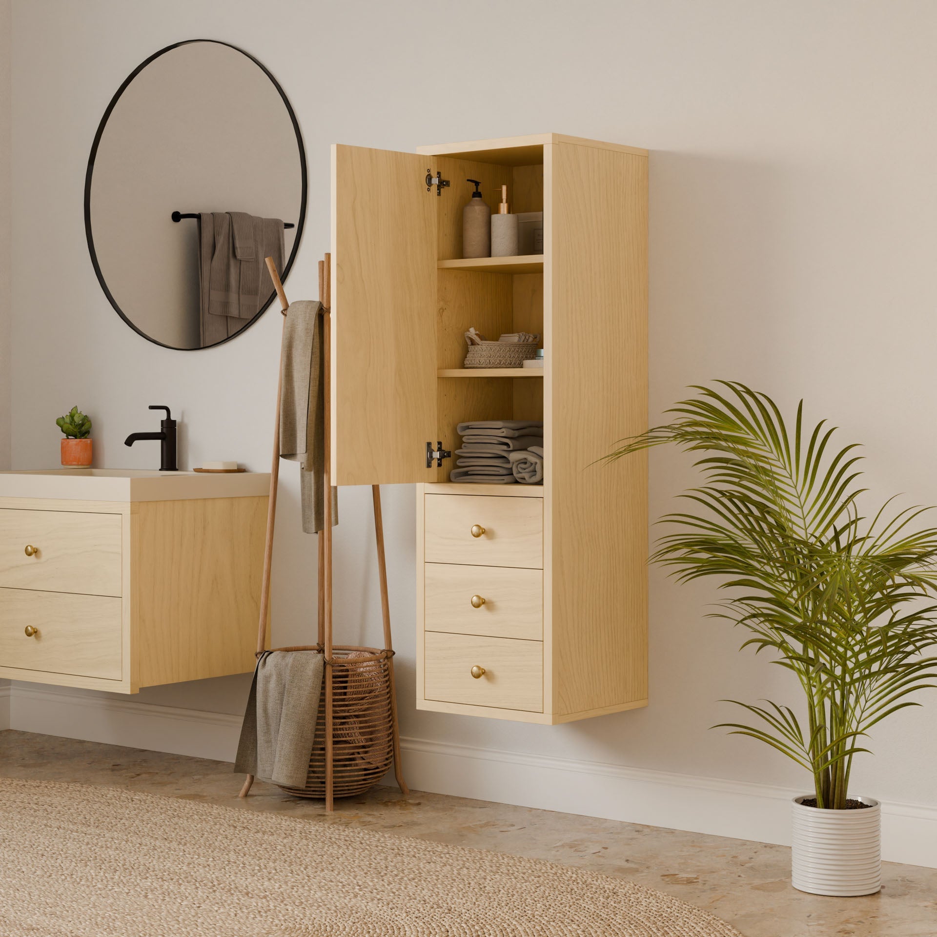 A minimalist bathroom showcases the Triple Drawer Linen Cabinet in Maple by Krovel Furniture Co. It features light wooden cabinets. Above the sink, a round mirror and black faucet are visible. A plant is beside the linen cabinet, while soft-close drawers house neatly stacked towels and toiletries.