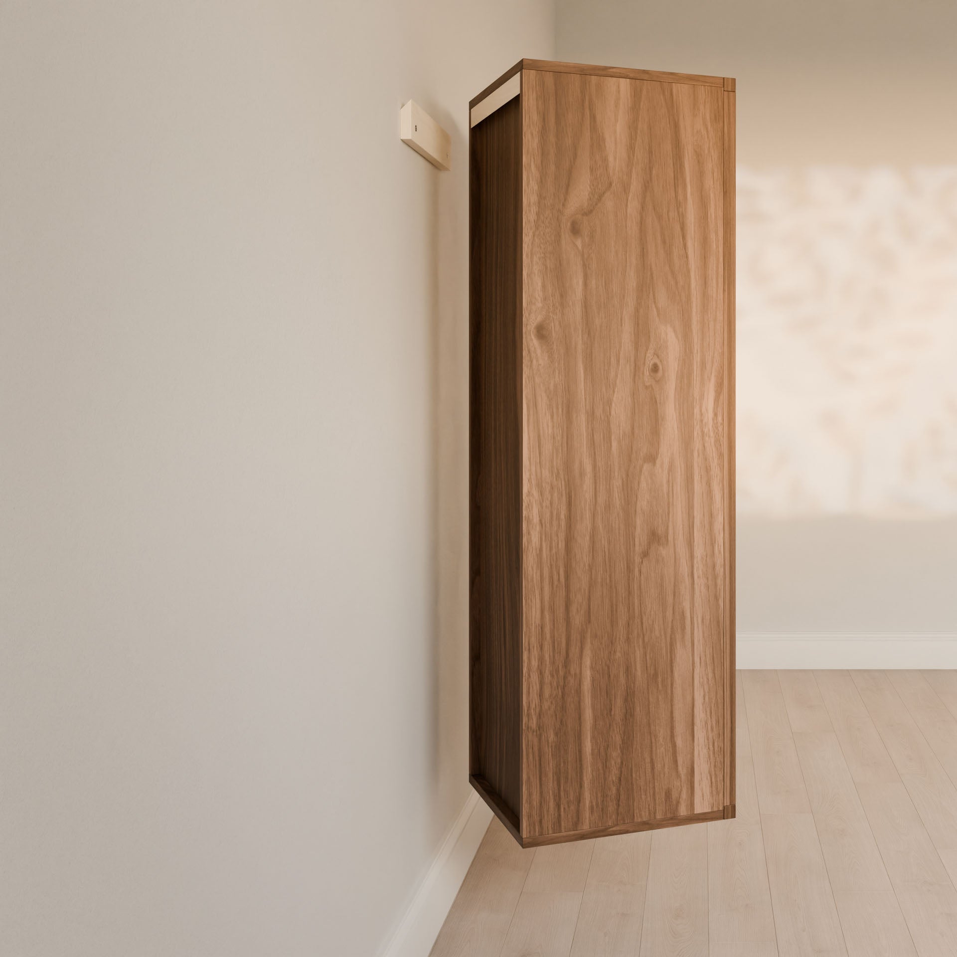 The Triple Drawer Linen Cabinet in Walnut by Krovel Furniture Co. is mounted at an angle on a light-colored wall in a minimalist room with wooden flooring, where sunlight casts soft shadows beside it, highlighting its sustainable construction.