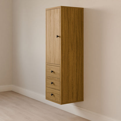 Krovel Furniture Co.s Triple Drawer Linen Cabinet in White Oak features a modern, tall design with a hardwood face frame, upper vertical panel door, and three black-knob drawers. It complements light-colored walls and wood flooring beautifully.