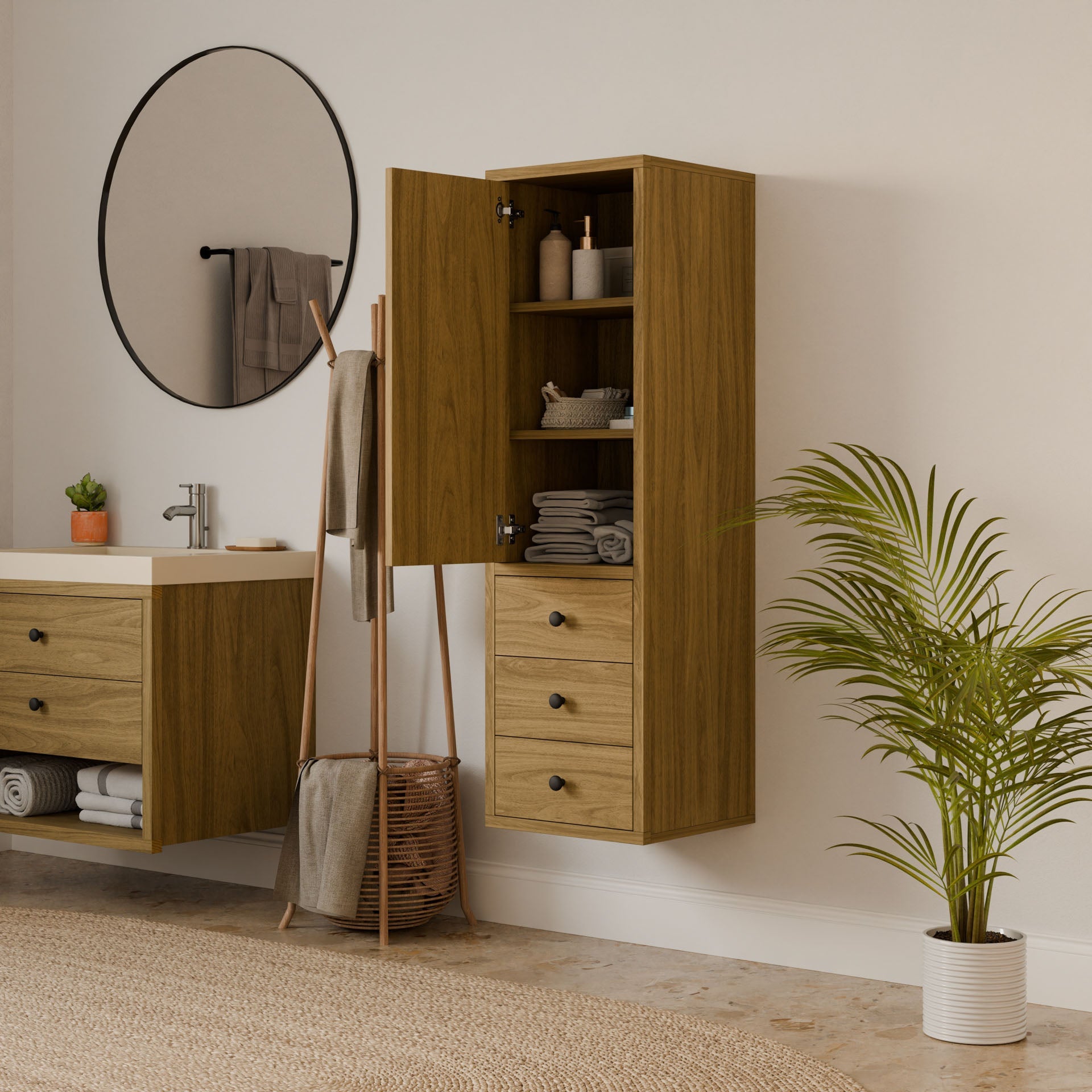 A modern bathroom features a Krovel Furniture Co. wooden vanity and Triple Drawer Linen Cabinet in White Oak, complemented by a round mirror. Neatly stacked towels grace the cabinet, while a floor basket holds another towel, and a potted plant adds greenery, all with eco-friendly construction.